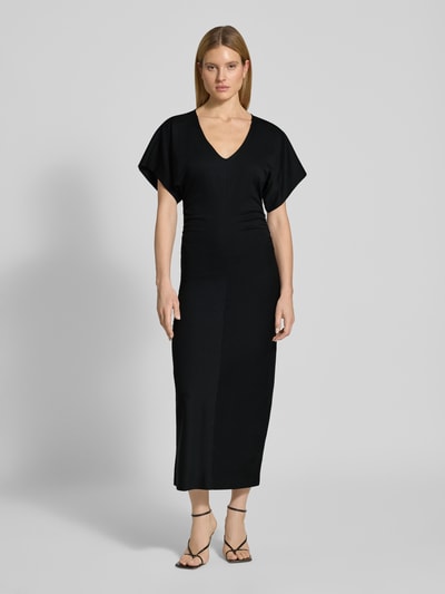 Vrouwenmodel draagt figurbetontes Maxikleid met V-hals Model 'PAMANTI' van Drykorn, lyocellmix met stretch, nauw aansluitend model, ruglengte bij maat S 136 cm, borstwijdte 36 cm, mouwlengte 17 cm, zwart, gladde stof, eenvoudige vormen, ganzkörperansicht van voren.