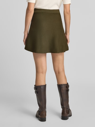 Frauenmodel trägt Ausgestellter Mini-Rock aus Viskose-Baumwoll-Mix Modell 'ELLY' von VERO MODA in uni Oliv, Feinstrick, Volant-Saum, Ganzkörperansicht Rückansicht.