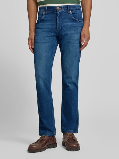 Männermodel trägt Straight Fit Jeans im 5-Pocket-Design Modell 'Greensboro' von Wrangler aus Baumwoll-Mix mit Stretch-Anteil, Gerader-Schnitt, Knopf-Reißverschluss, blaue Waschung, Bundweite 42 cm, Innenbeinlänge 79 cm, Nahaufnahme Oberkörper bis Füße von vorne.