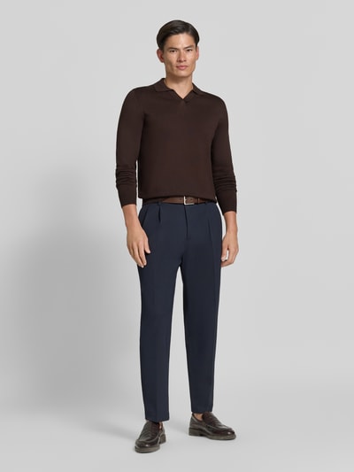 Männermodel trägt dunkelbraunen Strickpullover mit Viskose-Anteil Modell 'MANICA LUNGA' von MARKUP, Umlegekragen und gerippte Abschlüsse, Ganzkörperansicht von vorne.