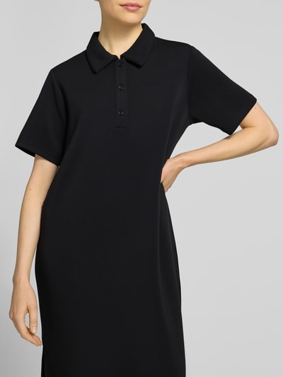 Frauenmodel trägt Polokleid mit Knopfleiste Modell 'Helle' von My Essential Wardrobe, schwarzer Material-Mix, gerader Schnitt, Nahaufnahme Oberkörper.