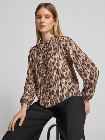Frauenmodel trägt Langarmbluse mit Rüschenfront von Marc Cain mit Animal Print und Stehkragen, Allover-Muster, Nahaufnahme Oberkörper.
