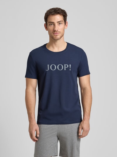 Männermodel trägt T-Shirt mit Logo und Rundhalsausschnitt von JOOP! Collection in Dunkelblau, Regular Fit, Vorderansicht, Nahaufnahme Oberkörper.