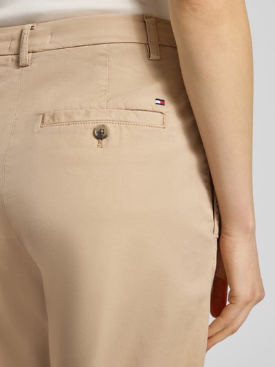 Kobieta nosi Slim Fit Chino aus Baumwoll-Mix von Tommy Hilfiger, efekt: jednolity kolor, mieszanka bawełny, detal: szlufki na pasek, kieszenie z tyłu, zapięcie na guzik i zamek błyskawiczny, krój slim fit, wpuszczane kieszenie boczne, widok z tyłu zbliżenie na biodra
