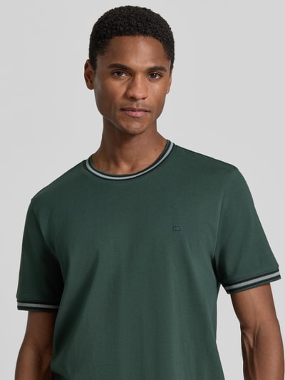 Männermodel trägt Regular Fit T-Shirt mit Logo-Stitching von Christian Berg Men aus Reine Baumwolle in Dunkelgrün, Nahaufnahme Oberkörper.