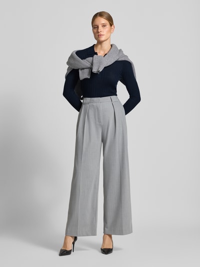 Vrouwenmodel draagt Henley-Shirt aus Wolle van Style Icon Collection, donkerblauw riblook, polokraag, skinny fit, puur katoen, met lange mouwen, tricotlook, ruglengte maat S 59 cm, mouwlengte maat S 66 cm, geheel vooraanzicht.