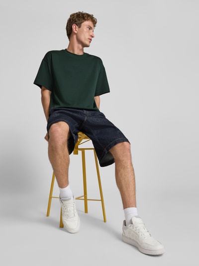 Männermodel trägt dunkelgrünes T-Shirt mit Rundhalsausschnitt Modell 'BARRON' von Jack & Jones, Relaxed Fit, Baumwoll-Mix, Ganzkörperansicht von vorne.