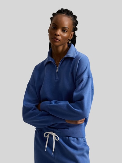 Frauenmodel trägt Sweatshirt mit Label-Stitching von Polo Ralph Lauren in Blau mit Polokragen, kurzem Reißverschluss, Nahaufnahme Oberkörper.
