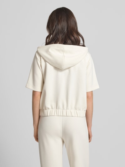 Frauenmodel trägt Sweatjacke mit Halbarm Modell 'Therese' von JOOP! in Creme mit Kapuze, Elastischer-Material-Mix, Gerader-Schnitt, Elastischer Bund, Rückansicht.
