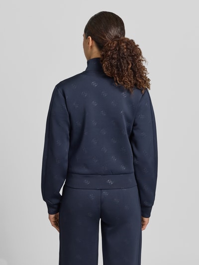 Frauenmodel trägt Sweatjacke mit Logo-Muster Modell 'CALISTA' von Guess Activewear aus Material-Mix mit Stretch-Anteil, Regular-Fit, Stehkragen, Reißverschluss und Eingrifftaschen, dunkelblau, Ganzkörperansicht Rückansicht.