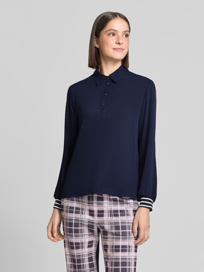 Modellka nosi koszulkę polo Regular Fit Poloshirt mit elastischen Ärmelabschlüssen od Marc Cain, kolor granatowy, koszulka z kołnierzykiem polo, elastyczne zakończenia rękawów, z długim rękawem, długość tyłu w rozmiarze 36: 63 cm, Ganzkörperansicht von vorne.