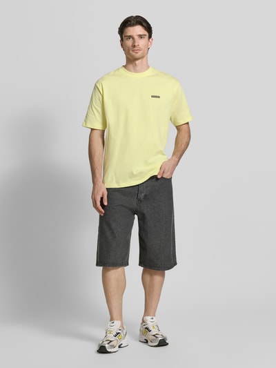 Männermodel trägt T-Shirt mit Label-Print Modell 'Baine' von WOODBIRD in Gelb, Reine Baumwolle, Regular-Fit, Ganzkörperansicht von vorne.