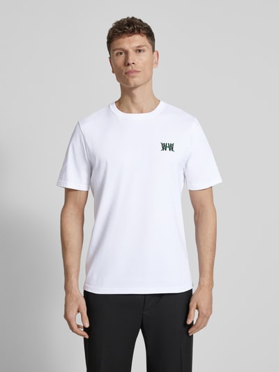 Męski model nosi Regular Fit T-Shirt mit Logo-Print Modell 'Bobby' von Wood Wood, bawełna, okrągły dekolt, długość tyłu 72 cm, Ganzkörperansicht von vorne.