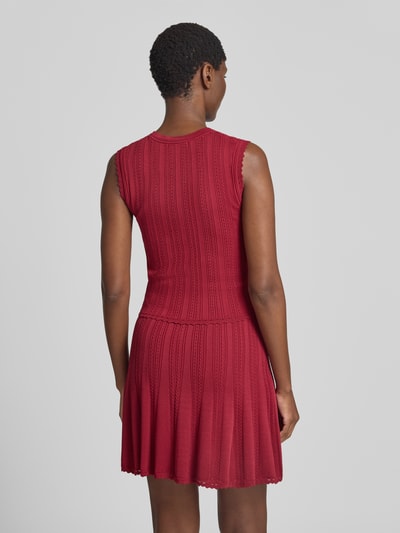 Frauenmodel trägt Stricktop in Pointelle-Strick mit kurzer Knopfleiste von GUESS, körpernaher Schnitt, Viskose-Mix, Ganzkörperansicht Rückansicht.