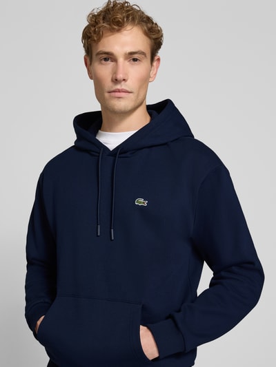 Männermodel trägt Relaxed Fit Hoodie aus katoenmix von Lacoste, donkerblauw, met kangoeroezak, Heren sweatshirt, Nahaufnahme Oberkörper