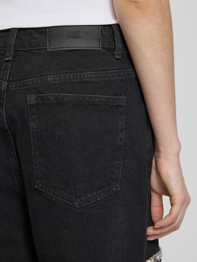 Frauenmodel trägt Straight Fit Jeans mit Cut Out von Karo Kauer, schwarze Baumwoll-Elasthan-Mix, 5-Pocket-Design, Ziersteinbesatz, Detailaufnahme Rückansicht.