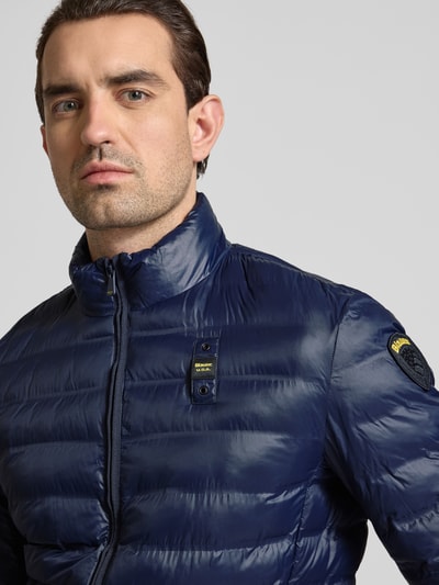 Männermodel trägt navy Regular Fit Jacke in Stepp-Optik Modell 'Sewall' von Blauer Usa mit Logo-Patch, Nahaufnahme Oberkörper. Rückenlänge 70 cm, Schulterbreite 44 cm, Brustweite 52 cm, Ärmellänge 64 cm, gefütterter Stehkragen, Zweiwege-Reißverschluss, Eingrifftaschen.