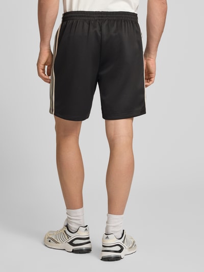 Männermodel trägt Regular Fit Sweatshorts mit elastischem Bund Modell 'RIBER' von Only & Sons, Optik: Unifarben, Kontraststreifen, Eingrifftaschen, Ganzkörperansicht Rückansicht.