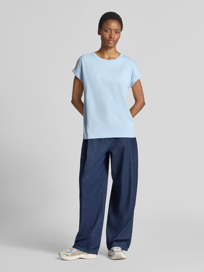 Frauenmodel trägt hellblaues Loose Fit T-Shirt aus reiner Baumwolle Modell 'IDAARA' von ARMEDANGELS, kombiniert mit dunkelblauer Hose, Ganzkörperansicht von vorne. Damen T-Shirt von ARMEDANGELS.