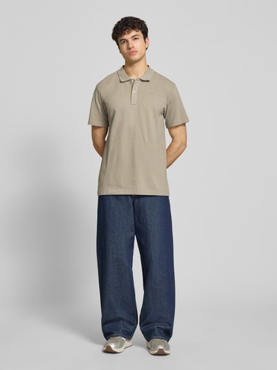 Męski model nosi Regular Fit Poloshirt mit Logo od G-Star Raw, beżowa bawełna, gładka faktura, guzikowa listwa, długość tyłu 74 cm, Ganzkörperansicht von vorne.