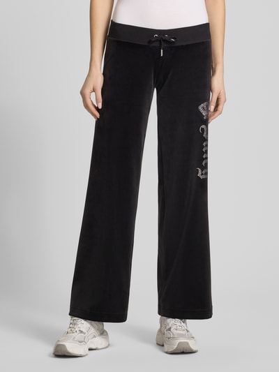 Kobiece model prezentuje Sweatpants mit Ziersteinbesatz Modell 'GOTHIC CROWN' von Juicy Couture, czarny materiał z elastycznym pasem i zdobieniami z dżetów, krój straight fit, materiał z domieszką stretchu, długość wewnętrzna 78 cm w rozmiarze S, widok całej sylwetki z przodu.