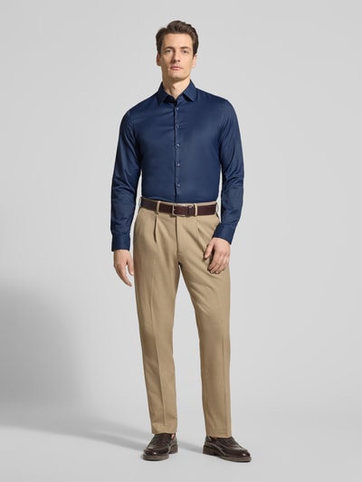 Männermodel trägt Slim Fit Business-Hemd mit Kentkragen von Jake*s in Dunkelblau, Material-Mix mit Stretch-Anteil, Knopfleiste, Ganzkörperansicht von vorne. Rückenlänge 71 cm, Schulterbreite 45 cm, Ärmellänge 65 cm bei Größe 39/40.