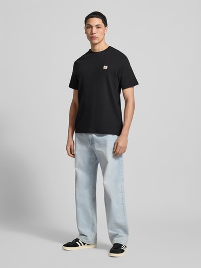 Männermodel trägt Regular Fit T-Shirt mit Logo-Patch von Calvin Klein Jeans, Baumwoll-Mix, Strukturmuster, Rundhalsausschnitt, Ganzkörperansicht von vorne.
