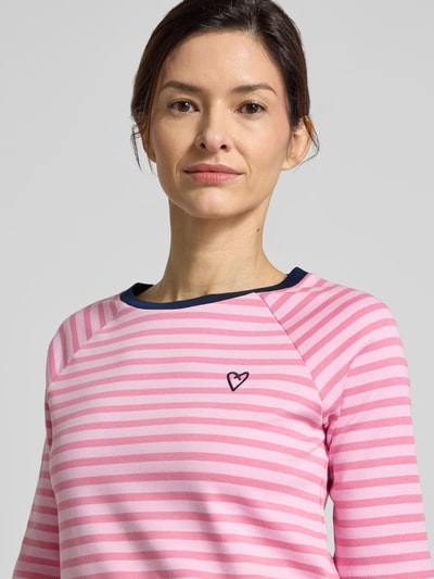 Frauenmodel trägt Shaped Fit T-Shirt aus reiner Baumwolle von Tom Tailor Denim, pink-weiß gestreift, Rundhals, Feinripp, Nahaufnahme Oberkörper.