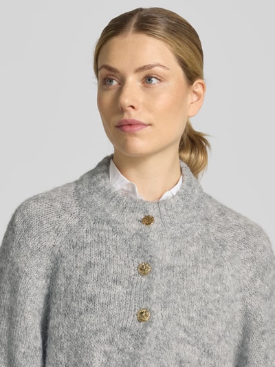 Frauenmodel trägt Relaxed Fit Cardigan mit Woll-Anteil Modell 'Benutta' von Neo Noir, elastyczna mieszanka materiałów z dodatkiem wełny, imitacja dzianiny, rękaw o dł. 1/2, listwa guzikowa, kolor szary, widoczna tekstura, Długość tyłu w rozmiarze 36: 54 cm, Długość rękawów w rozmiarze 36: 38 cm, zbliżenie na górną część ciała