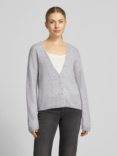 Frauenmodel trägt Relaxe-Fit Strickjacke aus Alpacka-Mix mit Woll-Anteil Modell 'C_Farano' von BOSS Orange in Melange-Optik, V-Ausschnitt, gerippte Abschlüsse, einreihige Knopfleiste, Label-Detail, Stricktextur, Ganzkörperansicht von vorne.