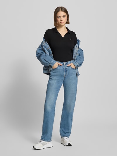 Frauenmodel trägt Longsleeve mit Label-Detail von Calvin Klein Jeans in Schwarz, Baumwoll-Elasthan-Mix, Slim-Fit, Polokragen, V-Ausschnitt, Jeans-Look, Ganzkörperansicht von vorne. Rückenlänge bei Größe S: 57 cm.