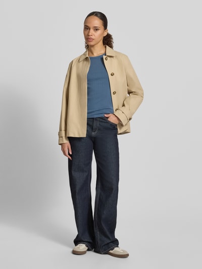 Frauenmodel trägt T-Shirt in Pointelle-Strick mit Rundhalsausschnitt von Jake*s Casual aus reiner Baumwolle, körpernaher Schnitt, blaue Farbe, feine Strickstruktur, kombiniert mit dunkler Jeans und beiger Jacke, Rückenlänge bei Größe S 51 cm, Ganzkörperansicht von vorne.