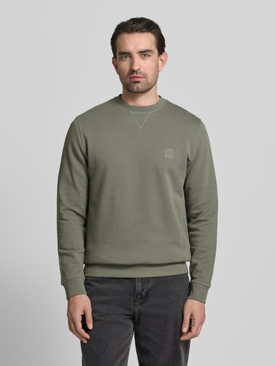Męski model nosi Relaxed Fit Sweatshirt aus reiner Baumwolle Modell 'WESTART' od BOSS Orange, kolor jednolity, naszywka z logo, okrągły dekolt, długi rękaw, materiał sweat, czysta bawełna, widok całej sylwetki z przodu.