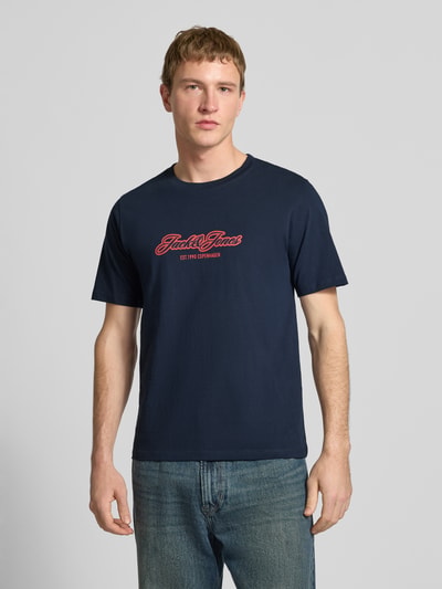 Männermodel trägt Regular Fit T-Shirt mit Logo-Print von JACK & JONES, reine Baumwolle, navyblau, Rundhalsausschnitt, Ganzkörperansicht von vorne.