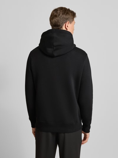 Männermodel trägt Hoodie mit Label-Stitching und Känguru-Tasche von Gant, schwarz, Baumwoll-Mix, Regular Fit, Ganzkörperansicht Rückansicht