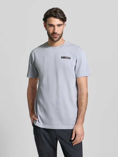 Męski model nosi Regular Fit T-Shirt mit Logo-Applikation von Under Armour z okrągłym dekoltem, bawełniany miks, kolor jasnoszary, Ganzkörperansicht von vorne