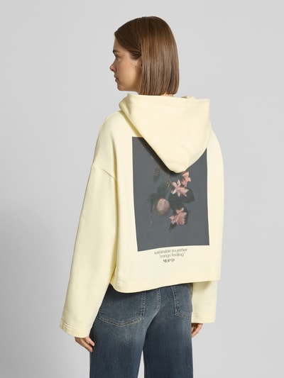 Frauenmodel trägt Boxy Fit Hoodie aus reiner Baumwolle von Marc O'Polo in Hellgelb mit floralem Print, Damen Hoodie von Marc O'Polo DENIM, Ganzkörperansicht Rückansicht.