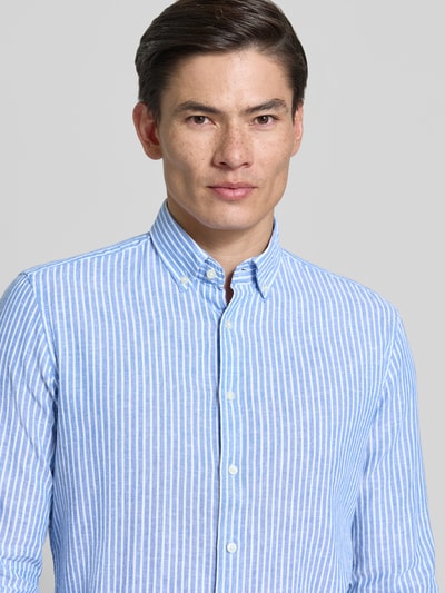 Männermodel trägt Slim Fit Freizeithemd aus Leinen-Mix Modell 'Stone' von CINQUE, blau-weiß gestreift, Button-Down-Kragen, Nahaufnahme Oberkörper. Leinen-Mix mit Baumwoll-Anteil, Langärmelig, Rückenlänge 75 cm, Schulterbreite 46 cm, Ärmellänge 67 cm, Größe M.