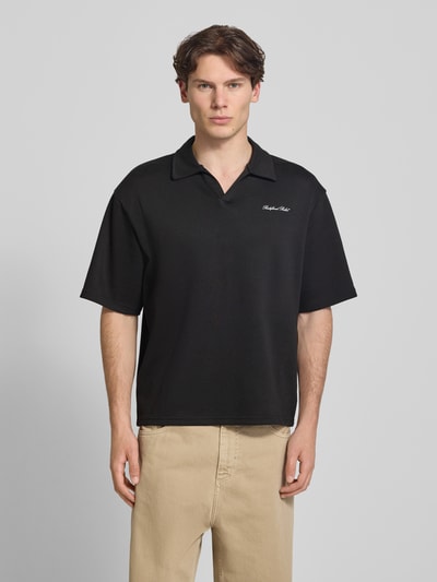 Männermodel trägt schwarzes Regular Fit Poloshirt mit Logo Modell 'Eddie' von Redefined Rebel aus Baumwoll-Mix, V-Ausschnitt, Rückenlänge 73 cm bei Größe M, Ganzkörperansicht von vorne.