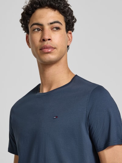 Männermodel trägt T-Shirt in Melange-Optik von Tommy Jeans in Dunkelblau mit Logo-Stitching, reine Baumwolle, Nahaufnahme Oberkörper.