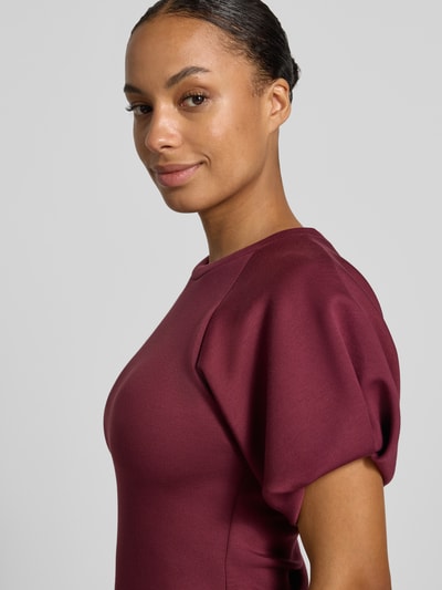 Vrouwenmodel draagt blouse met ballonmouwen van Rinascimento in bordeaux Materiaalmix met stretch, getailleerde pasvorm, ronde hals, ruglengte maat S 55 cm, mouwlengte maat S 27 cm, detailopname zijaanzicht