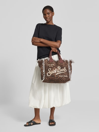 Vrouwenmodel draagt shopper met labelprint en franjes Model 'VANITY' van MC2 Saint Barth, puur katoen, hoofvak met ritssluiting, draagband, breedte maat 1: 37 cm, lengte maat 1: 32 cm, diepte maat 1: 22 cm, bandlengte schouderband maat 1: 48 cm. Volledige lichaamsvoorzijde.