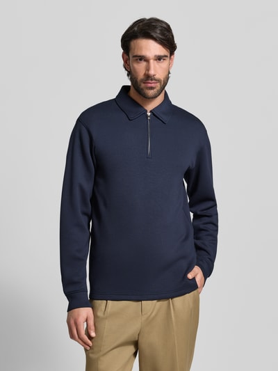 Männermodel trägt Regular Fit Poloshirt aus Viskose-Mix Modell 'EMANUEL' von SELECTED HOMME in Dunkelblau, unifarben, Ganzkörperansicht von vorne.