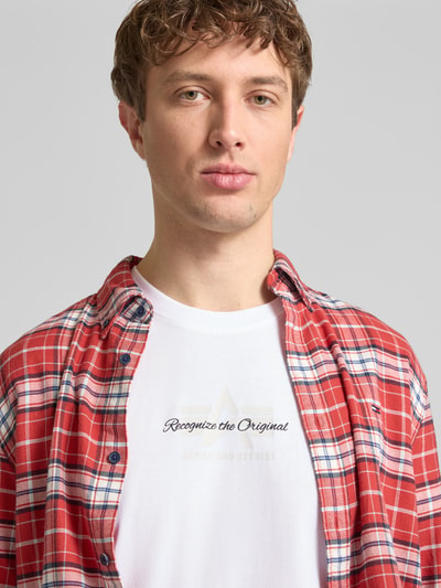 Männermodel trägt Alpha Industries T-Shirt mit Label-Detail Modell 'Foam', Reine Baumwolle, Gerader-Schnitt, Rundhalsausschnitt, Nahaufnahme Oberkörper.