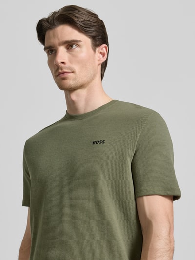 Männermodel trägt Regular Fit Pyjama-Oberteil aus Baumwoll-Mix Modell 'WAFFLE' von BOSS in Oliv, Label-Stitching, Nahaufnahme Oberkörper.