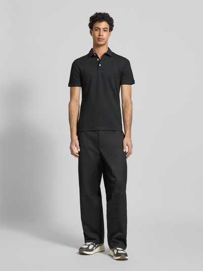 Männermodel trägt Slim Fit Poloshirt mit Viskose-Anteil Modell 'Paulos' von JACK & JONES, Baumwoll-Mix, Logo-Stitching, Ganzkörperansicht von vorne.