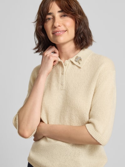 Frauenmodel trägt Strickpullover aus Baumwoll-Kaschmir-Mix mit Ziersteinbesatz von Luisa Cerano in Creme, Struktur sichtbar, Nahaufnahme Oberkörper, Regular Fit, Umlegekragen, Knopfleiste, 1/2-Arm, Rückenlänge 55 cm, Ärmellänge 29 cm.