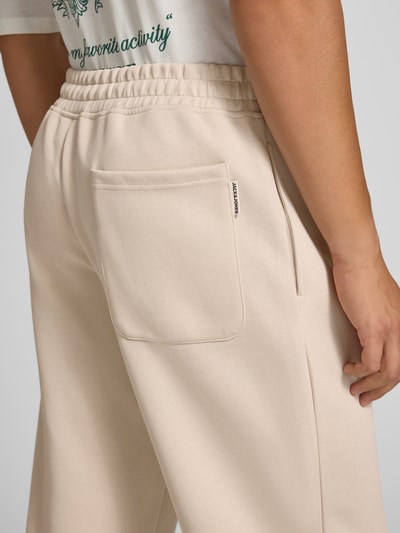 Männermodel trägt Straight Fit Sweatpants mit elastischem Bund von JACK & JONES in Beige, glatte Textur, Detailaufnahme Rückansicht. Material-Mix mit Baumwoll-Anteil, sichtbare Eingrifftasche, Innenbeinlänge bei Größe M: 76 cm.