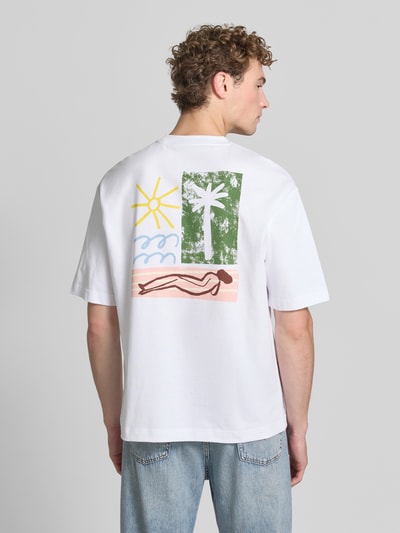 Männermodel trägt Relaxed Fit T-Shirt aus reiner Baumwolle Modell 'NORMAN' von Selected Homme, weiß mit buntem Print, Ganzkörperansicht Rückansicht. Herren T-Shirt.