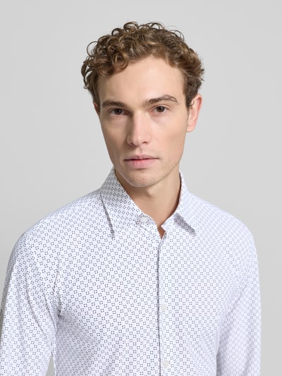 Männermodel trägt Slim Fit Freizeithemd mit Allover-Muster Modell 'P-ROAN-K-F-261' van BOSS in wit met zwarte print, Nahaufnahme Oberkörper, Kentkraag, lange mouwen, prestatie-stretchjersey.